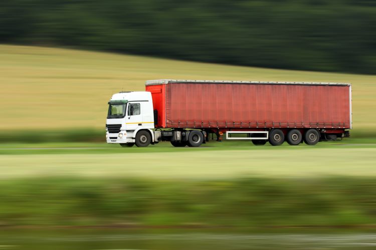large red truck speeding on highway with blurred countryside panorama in background